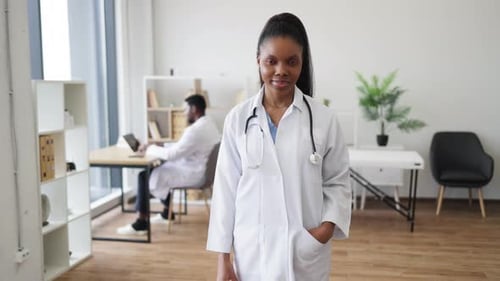 Smiling Female Doctor in White Coat in Bright Medical Office Setting