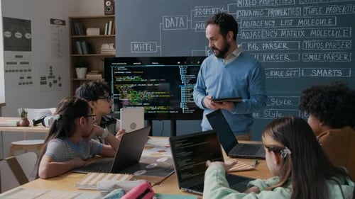 Reifer männlicher Programmierlehrer erklärt einer vielfältigen Klasse ein neues Thema