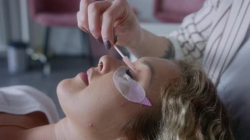 Esteticista penteando os cílios estendidos da mulher com uma escova