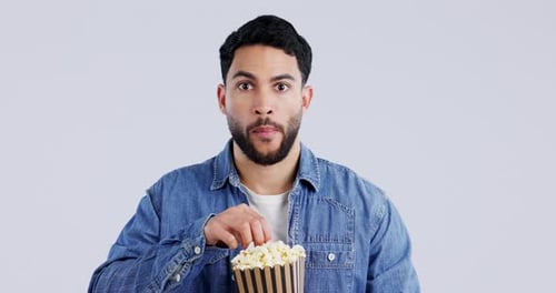 Eating popcorn, man and watching tv or horror movie with snack, theater food and series in studio