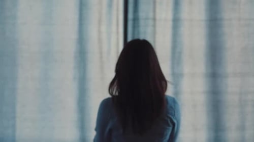 Woman Opens Curtains to Reveal City View