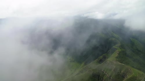Lush Mountain Landscape Enveloped in Thick Mist and Clouds Misty Green Mountainside with Overcast