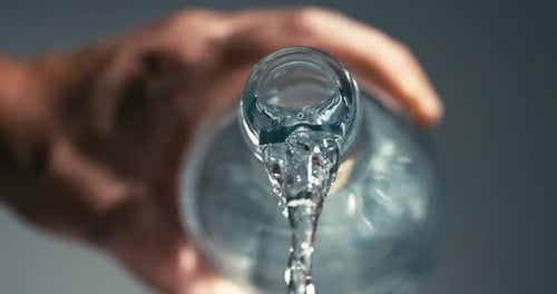 constant flow of healthy clear water poured out of glass bottle, importance of staying hydrated for
