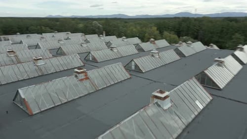 Fast Aerial fly over rooftop with glass windows in factory complex