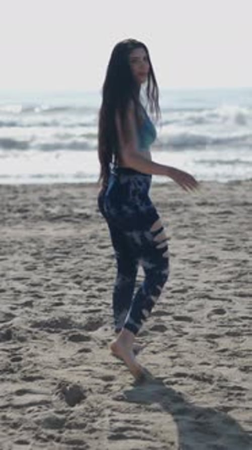 Woman Walks Barefoot on Sandy Beach Toward Ocean