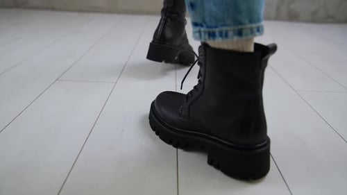 Model in jeans approaches camera and turns around. Low comfortable boots with laces demonstrated