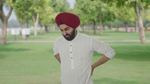 Sick Sikh Indian man suffering from back pain in park