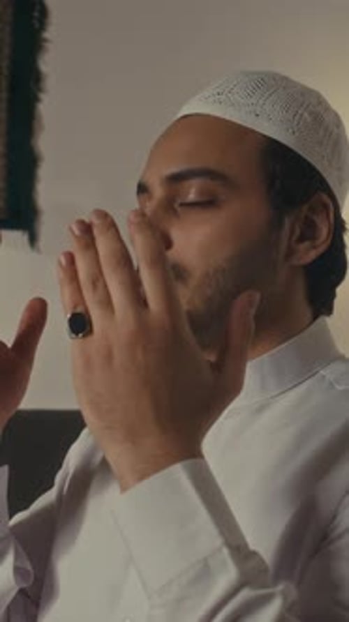 Vertikale Darstellung eines religiösen Muslims, der nach dem Gebet die Hände übers Gesicht legt
