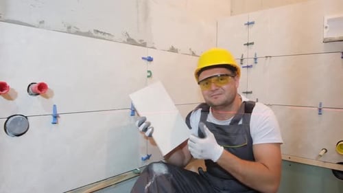 Man in Hard Hat Gives Thumbs Up Holding Tile