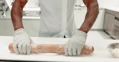 Baker Rolling Dough with Rolling Pin in Kitchen