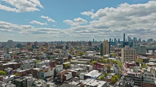 Drone flyover american neighborhood in Brooklyn and skyscraper in background during sunny day - NYC,