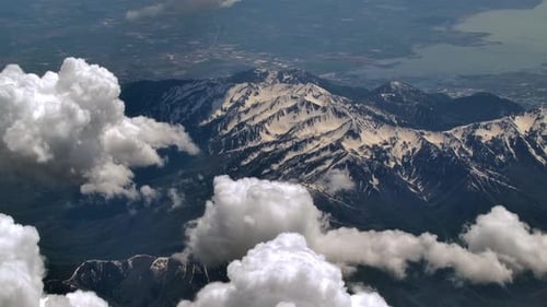 Aerial View of Snowy Mountain Range and White Fluffy Clouds - Flying