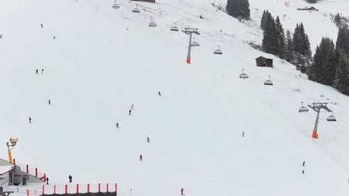 Skiers Descende Snowy Mountain Slope Next to a Chairlift in the Alps During Winter Holidays in
