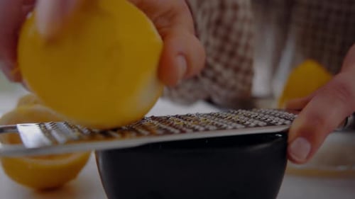 Küchenchefin reiben Zitronenschale mit einer Reibe in eine kleine Tasse