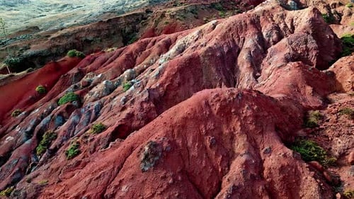 Aerial Eroded Red Cliffs with Rock Layers Stones Scattered Across Slopes