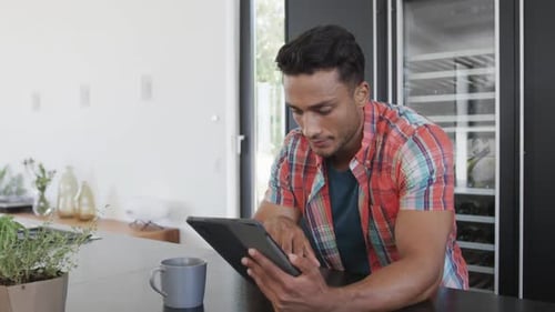 Young Adult Using Tablet at Kitchen Counter