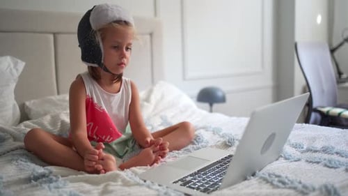 Child Using Laptop While Sitting on Bed