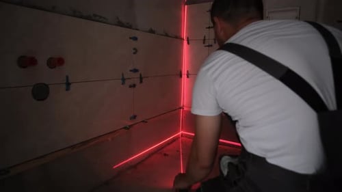 Der Meister legt Fliesen mit einem modernen vertikalen Laservideo auf den Boden