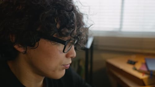 Man with Glasses Coding on Laptop with Multiple Monitors
