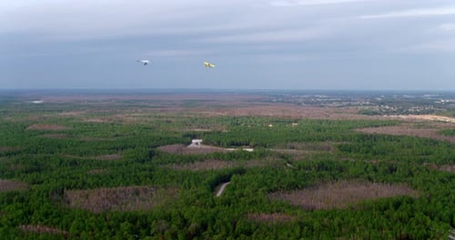Aerial shot of ultralight aircrafts flying over forested land