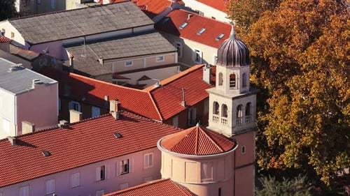 Aerial drone view of a small historic church with a rounded apse and a stone bell tower topped with