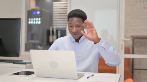 African Businessman Chatting Online on Laptop while Sitting in Office