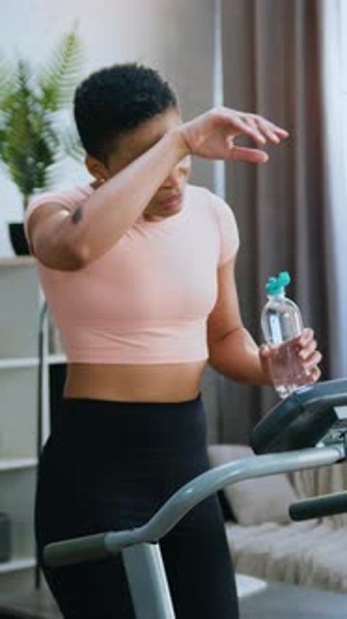 Woman Taking a Break on Treadmill Drinking Water