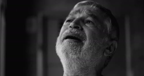 Elderly man gazing upward with tear-filled eyes, overwhelmed by unspoken sorrow,