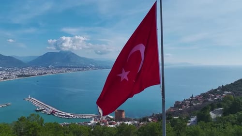 Aerial Video of a Beautiful Turkish Flag on a Flagpole Overlooking the Red Tower Blue Ocean and a