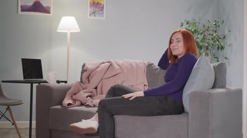 Woman Watching TV and Laughing on Couch