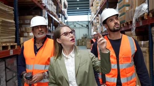 Warehouse Manager Inspecting Inventory with Workers in Logistics Center