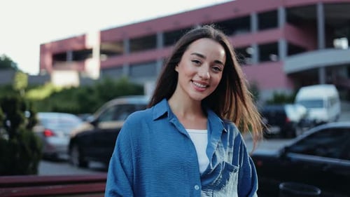 Portrait of a Happy Young Woman Smiling at the Camera While Standing in the City