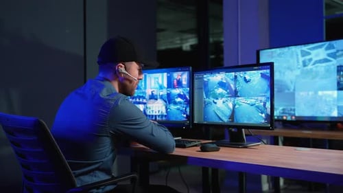 Security Officer with Headset Watching the Screens Talking on Radio in Control Room