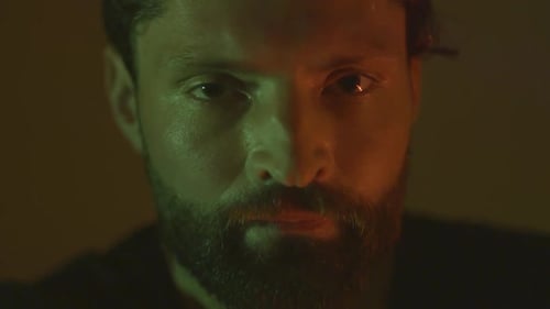 Closeup of serious bearded man looking at the camera in the dark room