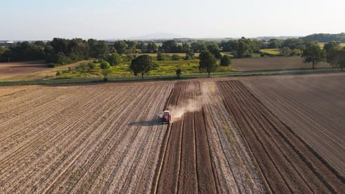 Tractor Working in Agricultural Field Cultivating and Plowing Dry Soil