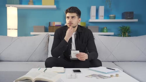 Stressed young man with anxiety unhappy with accumulated bills and bank debts.
