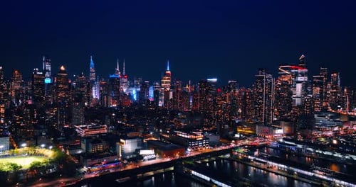 Approaching the luminous waterfront of the East River in New York at night.