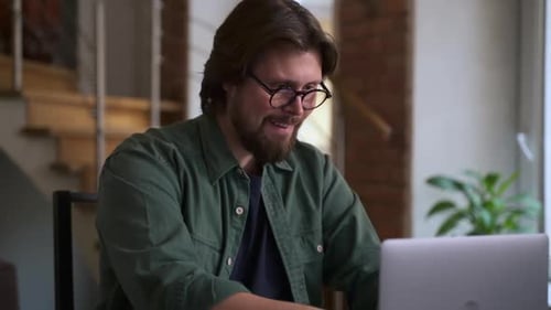 Man Working at Laptop Celebrates Success in Home Office