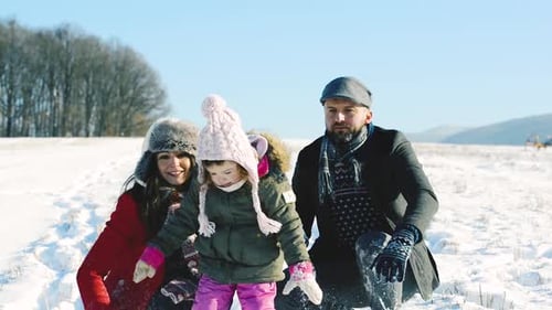 Father and Mother with Their Daughter Playing in the Snow