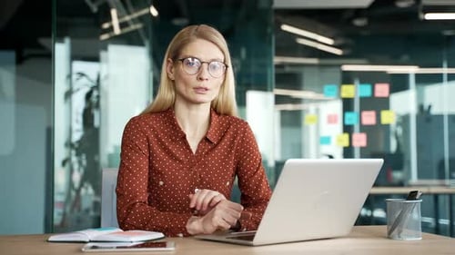 Portrait of a confident businesswoman sitting at desk at workplace in business office. Blonde woman
