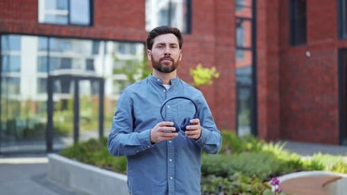 Man Takes Off Headphones Outdoors