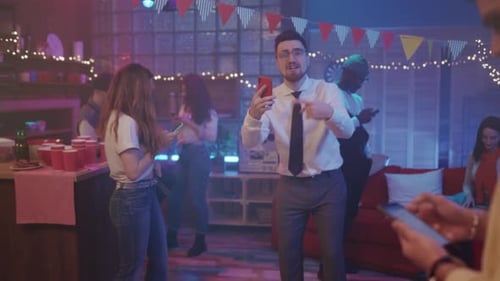 Young Adults Socializing at a Lively Party, Using Smartphones