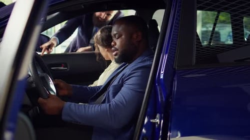 Couple Buying Car in Showroom with Salesman