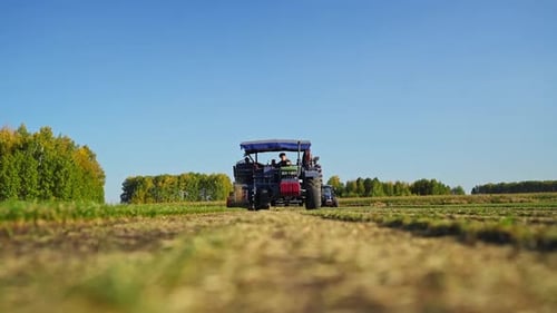 Tractor Driving Through Rural Field on Sunny Day