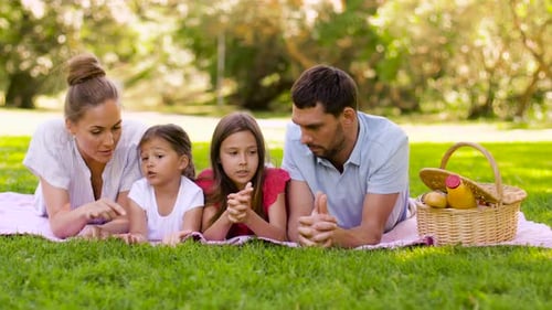 Happy Family Lying on Picnic Blanket in Park