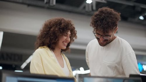 Customers choosing a laptop in electronics store in slow motion