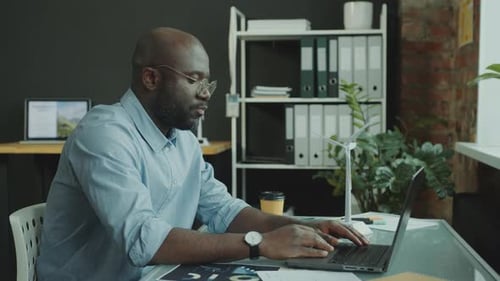 Engineer Working on Sustainable Energy Project on Laptop at Office Desk