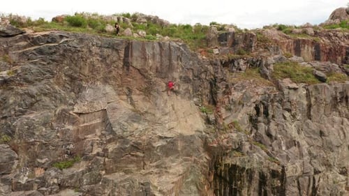 A zoom out video of a man climbing a mountain. A trail is running below a mountain. Breathtaking vie
