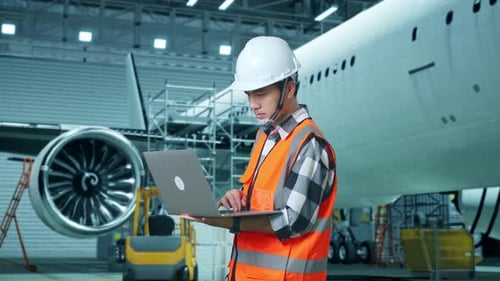 Asian Male Engineer Working On A Laptop While Aircraft Maintenance