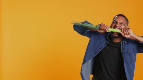 Young Person Biting on a Green Onion and Acting Silly in Studio